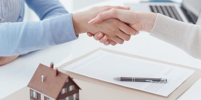 Real estate broker and customer shaking hands after signing a contract: real estate, home loan and insurance concept